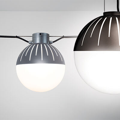 Two outdoor globe lights being hung by catenary cables as run and pendant